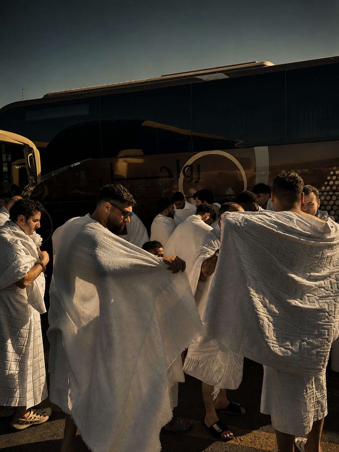 Reisegruppe legt vor dem Bus den Ihram an